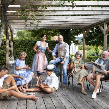 Die Familie der Hotelleitung sitzt in Drei Generationen in Tracht unter einer Pergola | © Hotel Bodenmaiser Hof