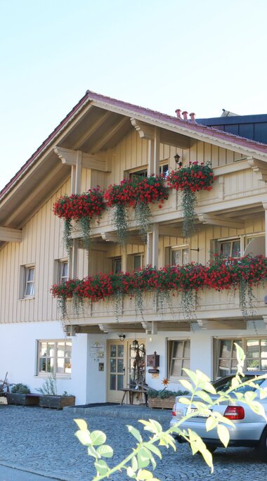 Frontansicht eines Gasthauses mit Blumen an den Balkonen. | © Haus Vierjahreszeiten