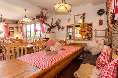 Blick in den urigen Gastraum des Ofenstüberls. Holztische mit rot-weiß karierten Tischdecken und Felle auf den Bänken. | © Ofentsüberl