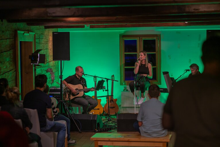 Auf eine grün beleuchtete Bühne in einem Altbau steht eine Sängerin auf der Bühne | © Bodenmais Tourismus & Marketing GmbH