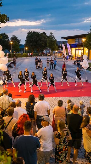 Auf einem mit rotem Teppich ausgelegten Platz tritt eine Tanzgruppe auf. Davor versammeln sich Zuschauer. | © Bodenmais Tourismus & Marketing GmbH