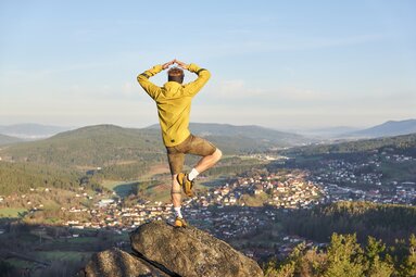 Ein Mann steht in einer Yoga Haltung auf einem Berg. | © Bodenmais Tourismus & Marketing GmbH